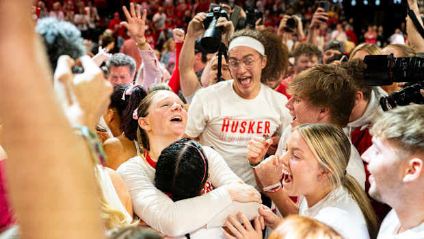 Feb 11, 2024; Lincoln, Nebraska, USA; The Nebraska Cornhuskers celebrate as fans storm the court after defeating the Iowa Hawkeyes at Pinnacle Bank Arena.